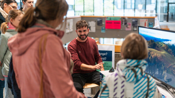Ein Wissenschaftler im Gespräch mit interessierten Gästen bei der Wissenschaftsnacht an der Universität Regensburg.