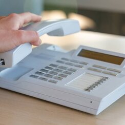 Person, die Hörer abnimmt von Telefon an der Uni Regensburg