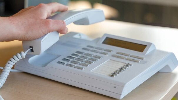 Person, die Hörer abnimmt von Telefon an der Uni Regensburg