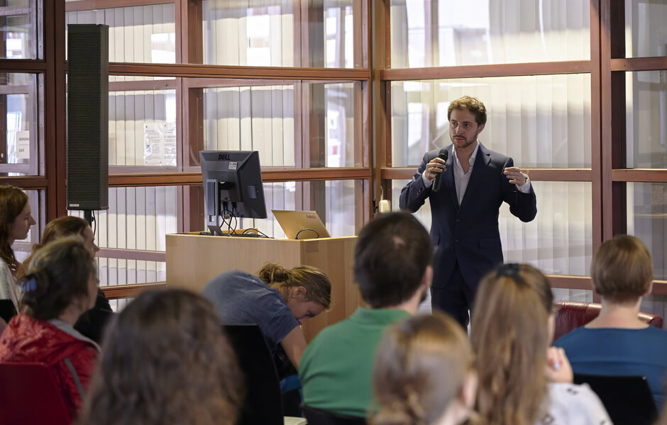 Mann referiert stehend, im Vordergrund Konferenzpublikum