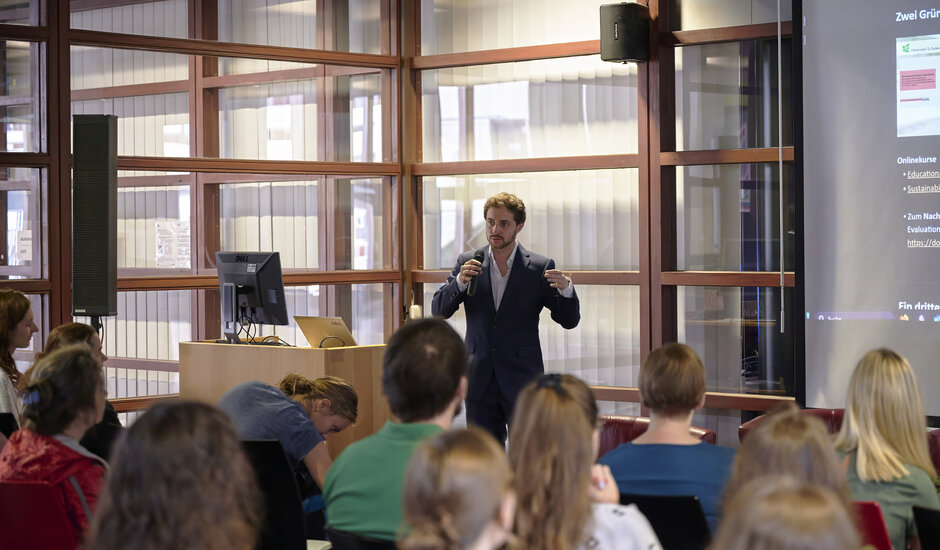 Mann referiert stehend, im Vordergrund Konferenzpublikum