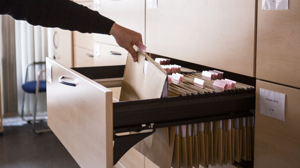 Person, die etwas aus einem Aktenschrank an der Uni Regensburg herausnimmt