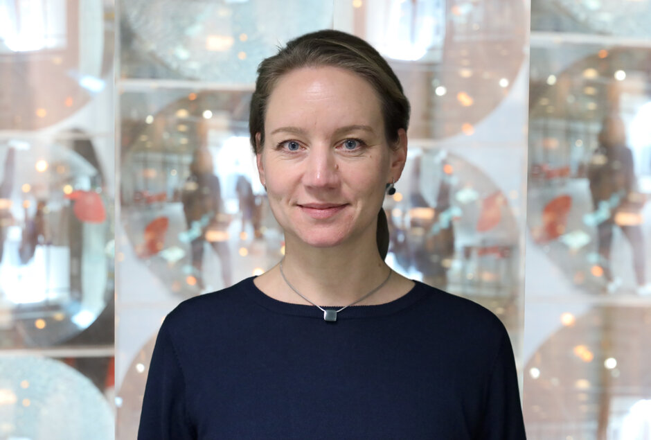 Eine Frau mit zurückgekämmten blonden Haaren blickt in die Kamera.