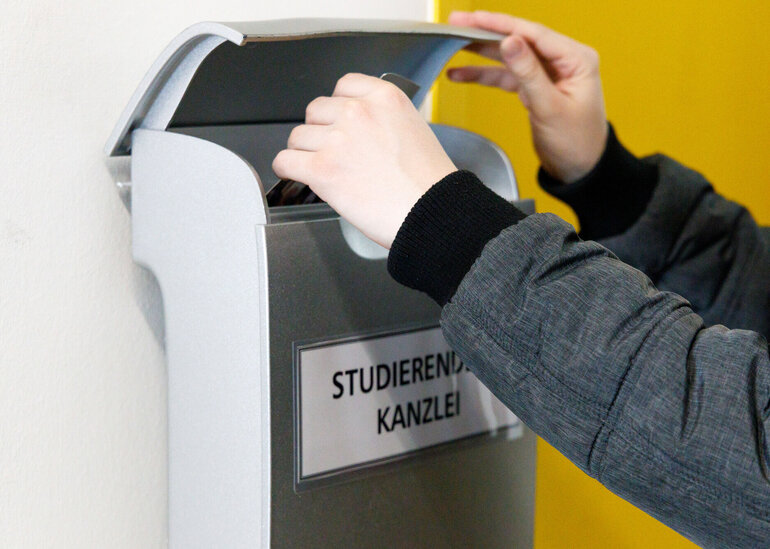 Jemand wirft etwas in den Briefkasten der Studierendenkanzlei