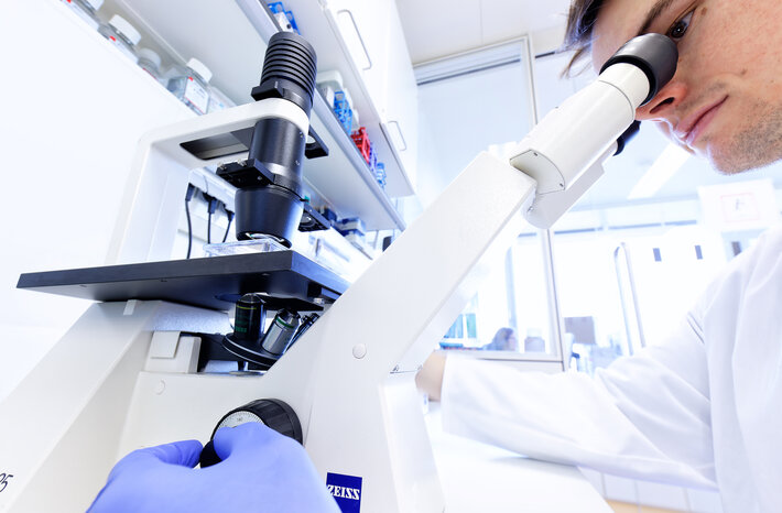 Mikroskop und Person im Labor (öffnet Vergrößerung des Bildes)
