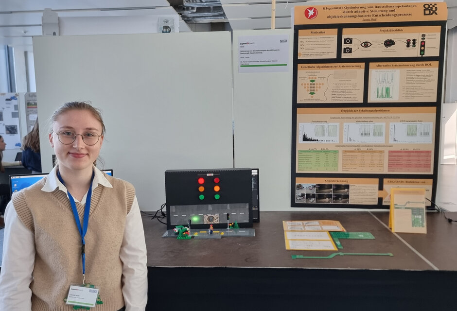 Eine junge Frau steht neben einem Versuchsaufbau und blickt lächelnd in Richtung Kamera.