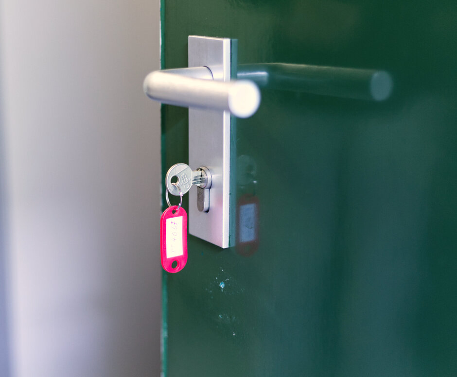 Türklinke mit Türschloss, in dem ein Türschlüssel mit Anhänger steckt