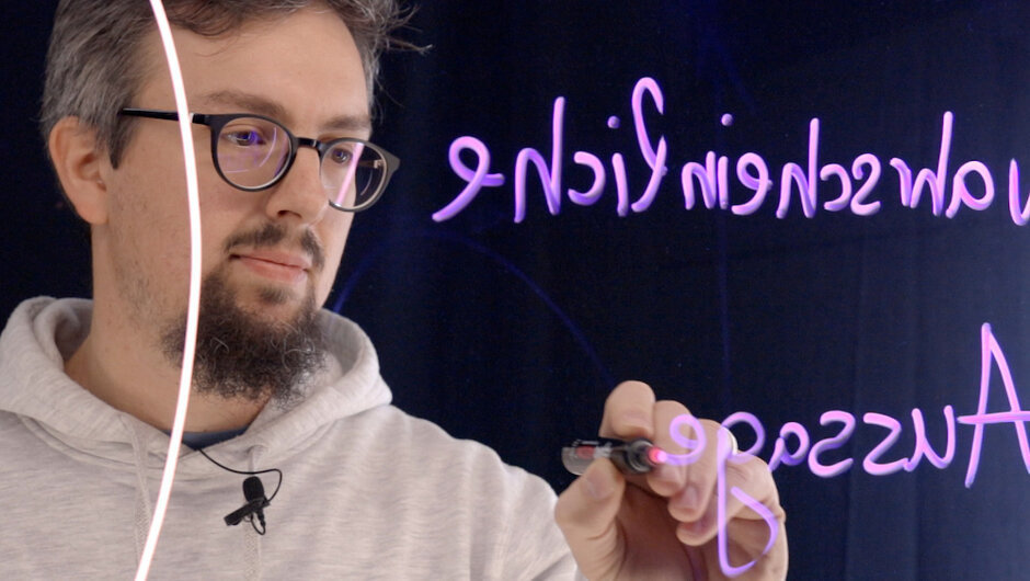 Ein Mann schreibt an eine transparente Tafel