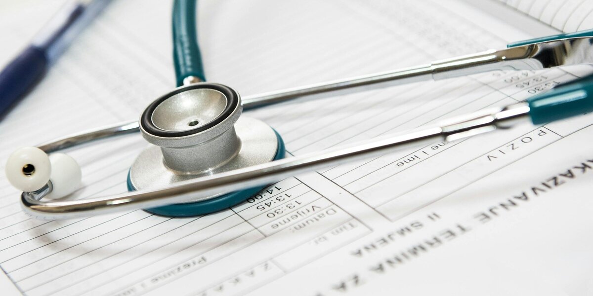 Stetoskop und Stift liegen auf medizinischen Unterlagen.