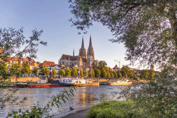 Blick auf die Donau, das südliche Ufer, Ausflugsschiffe und die Regensburger Altstadt. Im Hintergrund die Domspitzen. (öffnet Vergrößerung des Bildes)