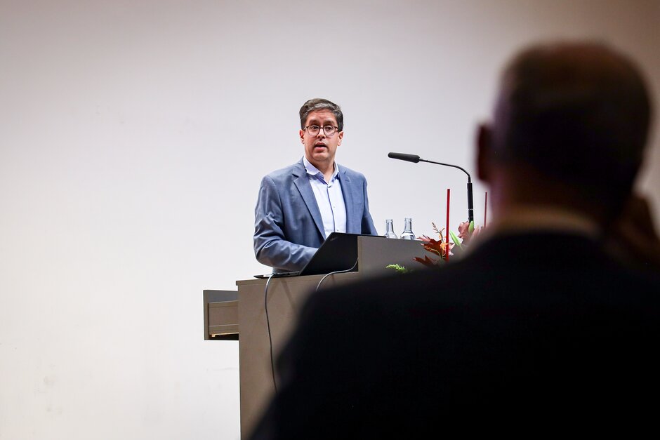 Mann mit Brille an Rednerpult (öffnet Vergrößerung des Bildes)