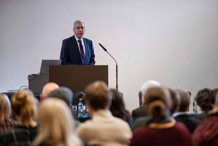 Ein älterer Mann mit grauen Haaren und Anzug steht an einem Rednerpult und spricht zu einem vor ihm sitzenden Publikum. (öffnet Vergrößerung des Bildes)