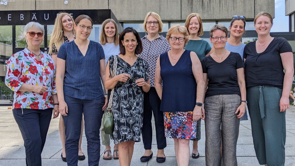 A group of eleven women lined up in two rows for a group photo.