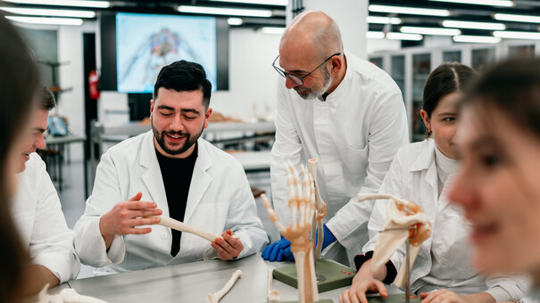 Ein Professor im Gespräch mit einem Studierenden, der anatomische Modelle betrachtet.