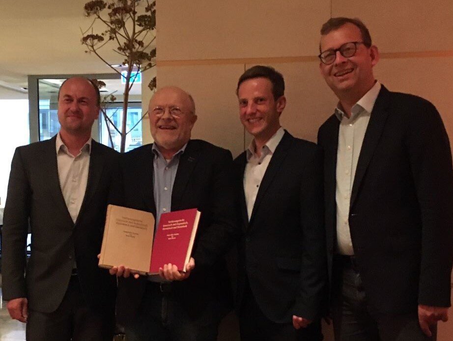 Das Bild zeigt Prof. Pieroth, der das Buch hält, und die drei Herausgeber Prof. Görisch, Hartmann und Kingreen bei der Übergabe. (öffnet Vergrößerung des Bildes)