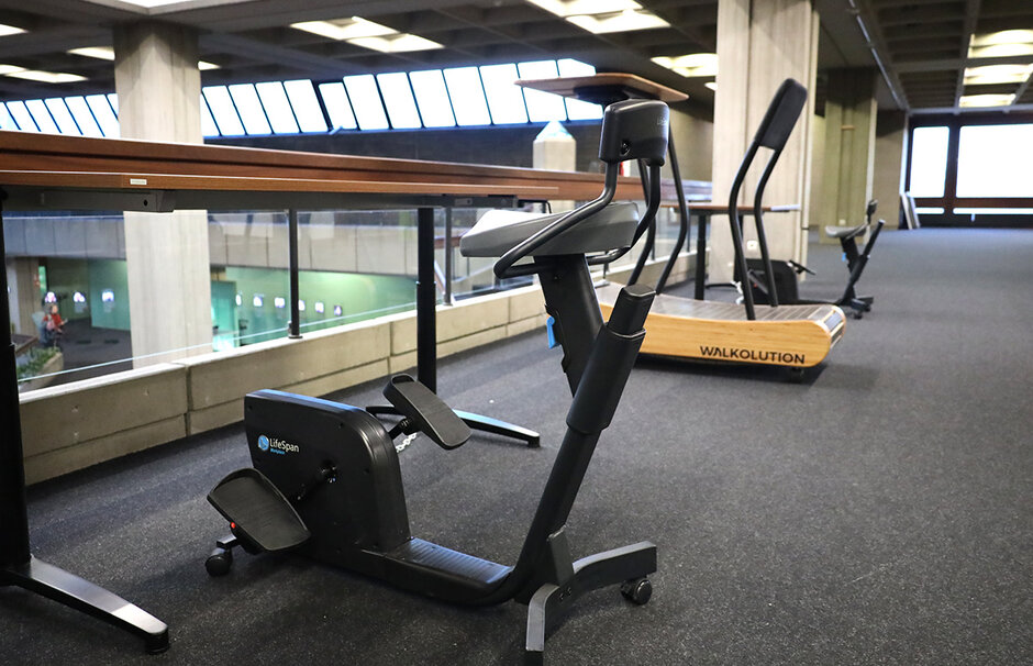 “Deskbike”, im Hintergrund “Walkolution”, beide Fitnessgeräte mit höhenverstellbaren Schreibtischen (öffnet Vergrößerung des Bildes)
