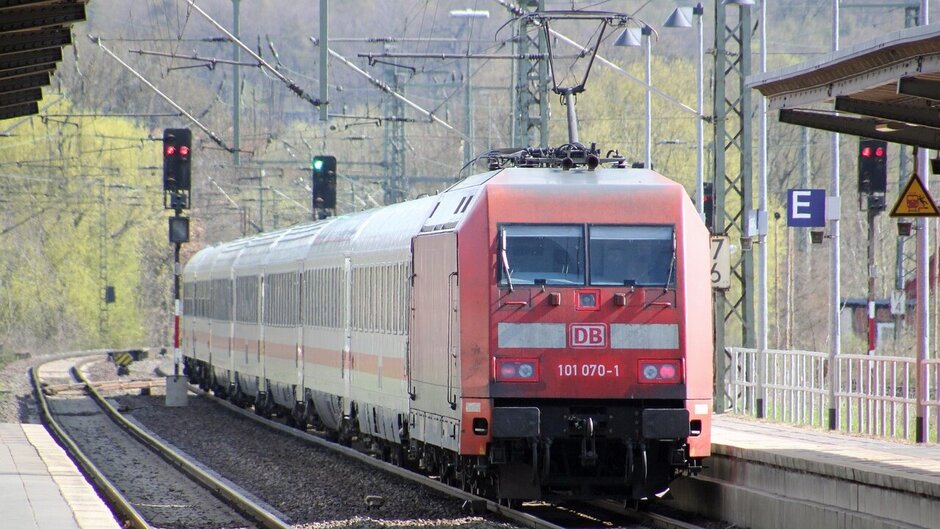 Man sieht einen roten Regionalzug in einen Bahnhof einfahren. 