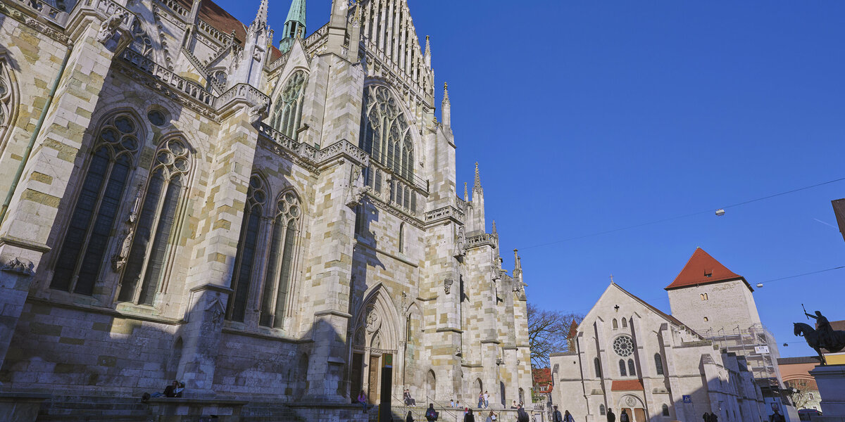 Die Fassade des gotischen Doms in Regensburg bei blauem Himmel in der Abendsonne.