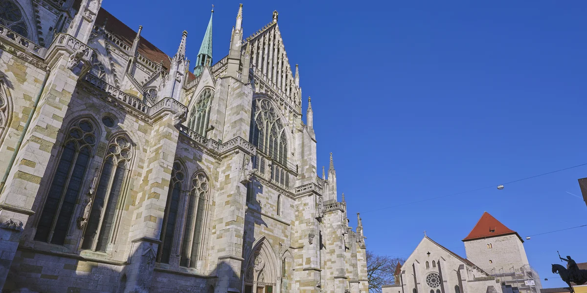 Die Fassade des gotischen Doms in Regensburg bei blauem Himmel in der Abendsonne.