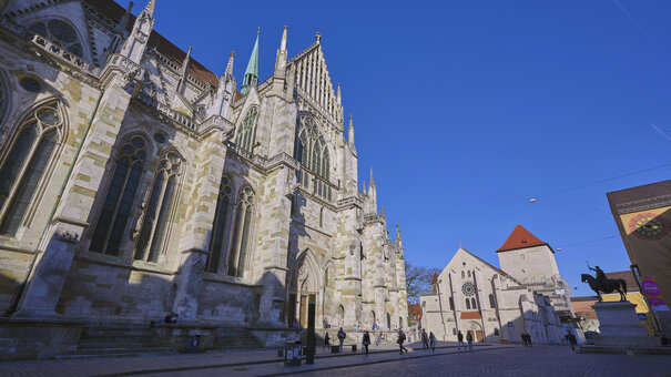 Die Fassade des gotischen Doms in Regensburg bei blauem Himmel in der Abendsonne.