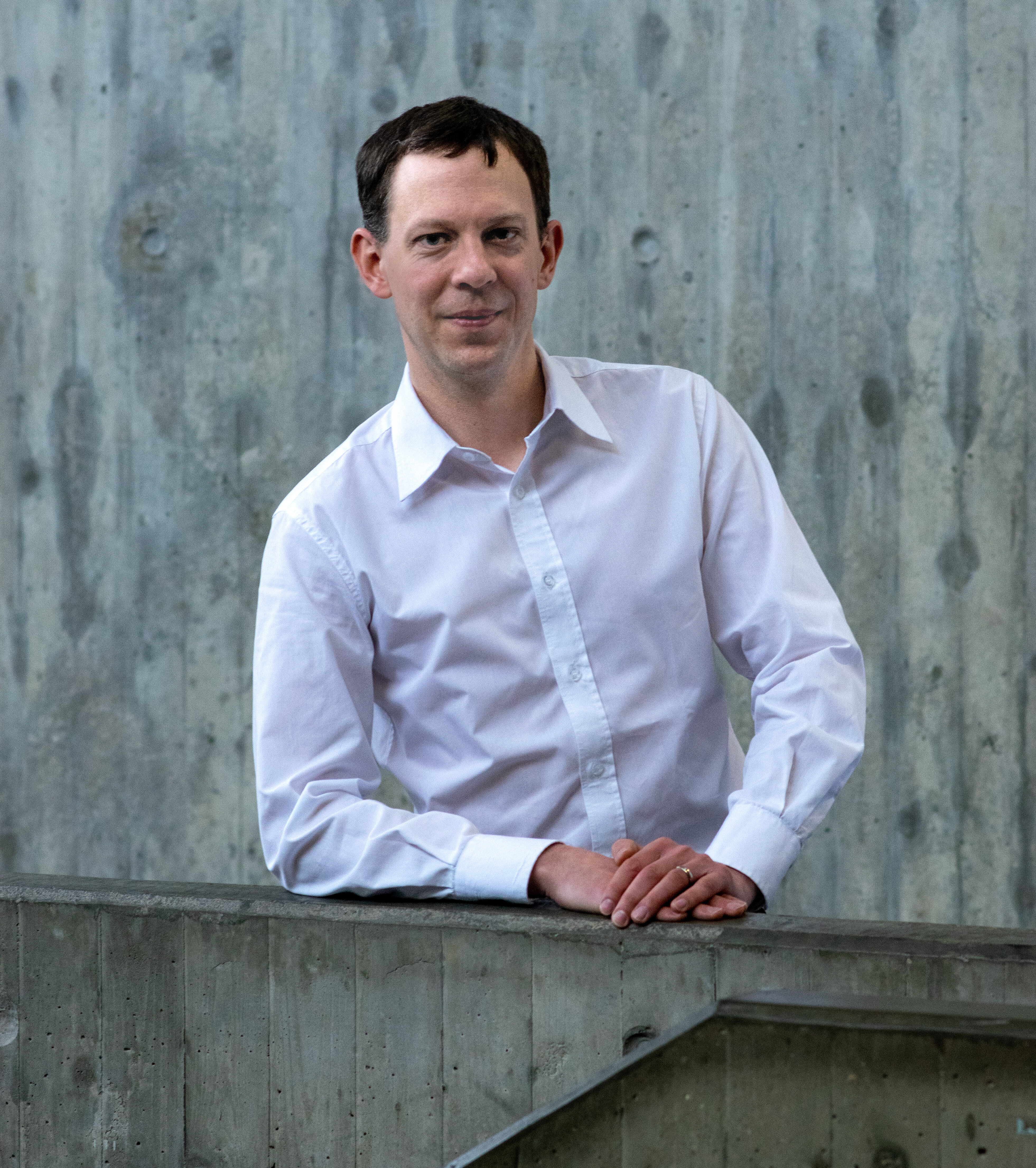 Ein Mann mit hellblauem Hemd lächelt in die Kamera.