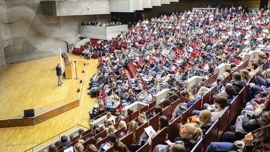 Riesiger Hörsaal mit voll besetzen Plätzen, von oben (öffnet Vergrößerung des Bildes)