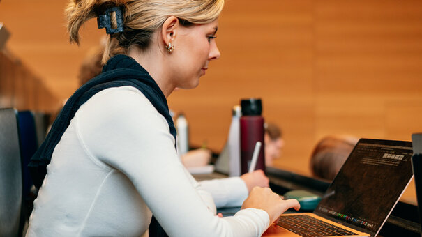 Eine Studentin mit Laptop sitzt in einem Hörsaal der Universität Regensburg.