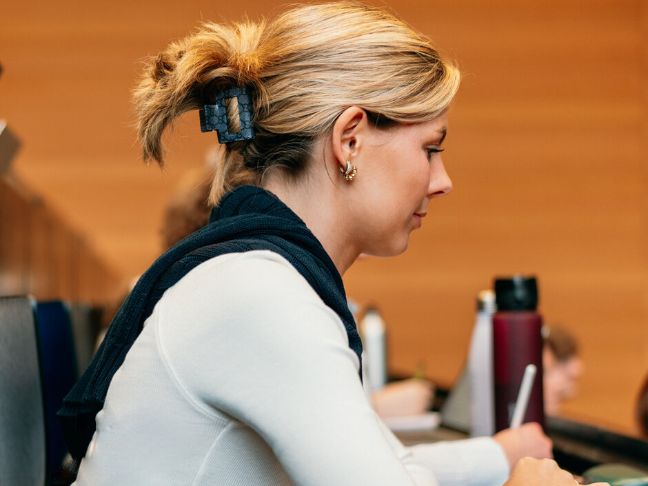 Eine Studentin mit Laptop sitzt in einem Hörsaal der Universität Regensburg.