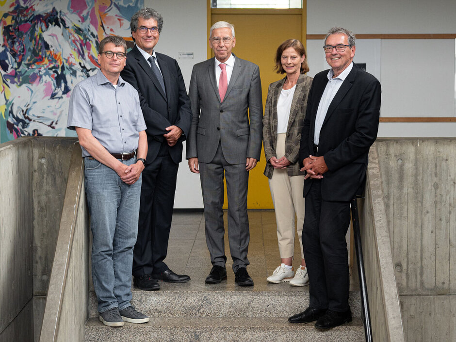Fünf Personen stehen in einem lockeren Halbkreis im Treppenhaus eines öffentlichen Gebäudes. (öffnet Vergrößerung des Bildes)