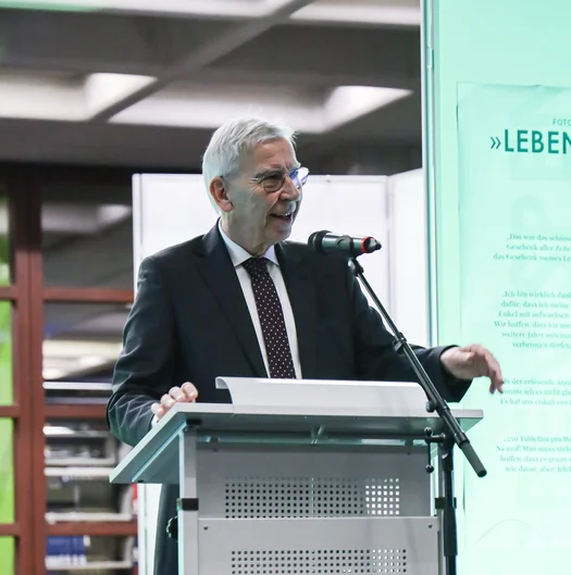 Ein Mann am Rednerpult spricht in ein Mikrofon.  (öffnet Vergrößerung des Bildes)