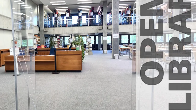 Innenansicht einer modernen, zweigeschossigen Bibliothek mit offenen Regalen, Leseplätzen und Servicebereich. Rechts im Bild steht vertikal der Schriftzug „OPEN LIBRARY“. (öffnet Vergrößerung des Bildes)