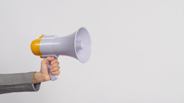 Hand is hold megaphone and wear grey suit on white background.
