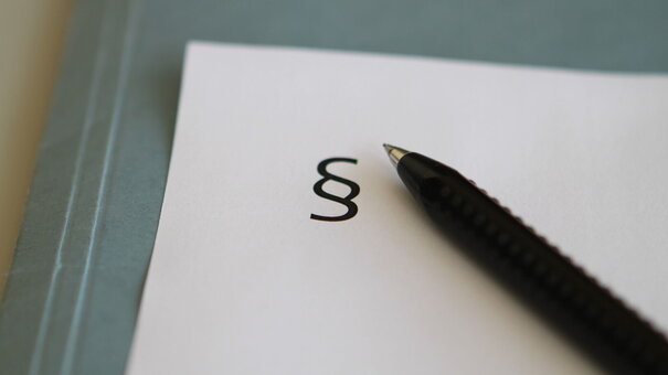 Paragraphenzeichen und Kugelschreiber