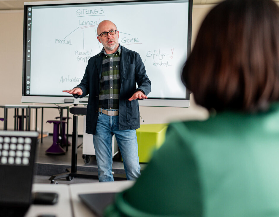 Ein Dozent im Gespräch mit einer Gasthörerin