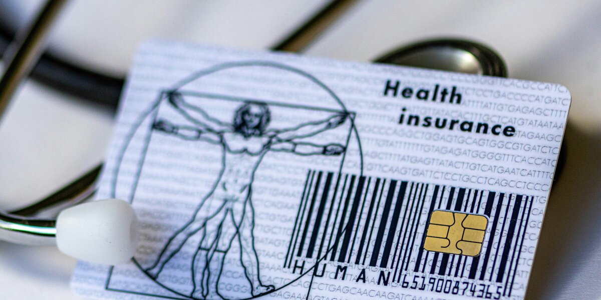 Auf einem Tisch liegt eine Krankenkassenkarte. Man sieht außerdem Teile eines Stethoskops. 