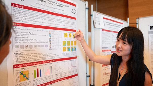 Eine junge Frau erläutert ein wissenschaftliches Plakat.