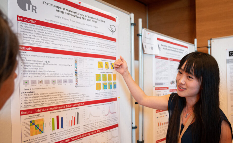 Eine junge Frau erläutert ein wissenschaftliches Plakat.