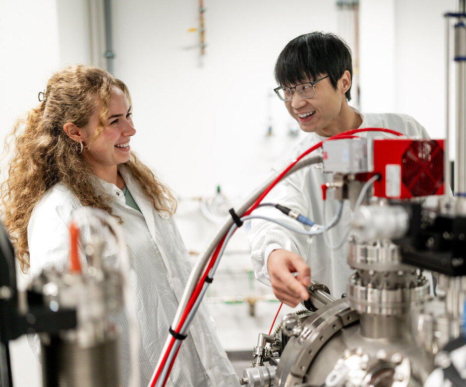 Zwei junge Forschende, die an einem Gerät stehen.