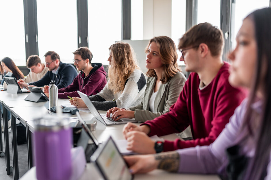 Studierende sitzen an einer Tischreihe in einem Seminarraum an der Universität Regensburg