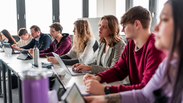 Studierende sitzen an einer Tischreihe in einem Seminarraum an der Universität Regensburg