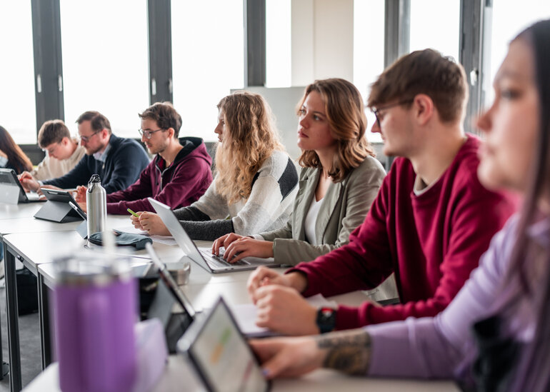 Studierende sitzen an einer Tischreihe in einem Seminarraum an der Universität Regensburg