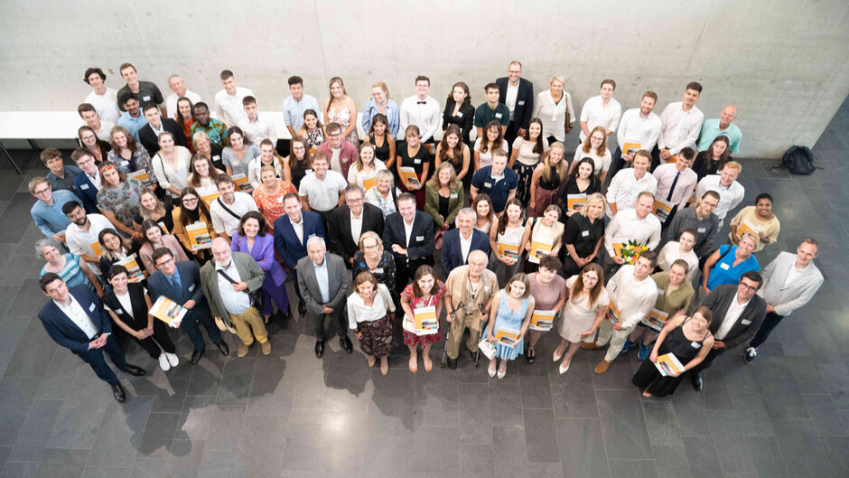 Ein von oben aufgenommenes Gruppenfoto mit vielen Personen. Sie blicken alle nach oben, in Richtung Kamera. (öffnet Vergrößerung des Bildes)