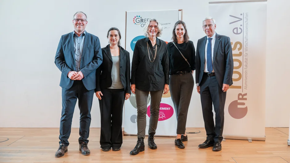Gruppenfoto von zwei Männern und drei Frauen, die auf einer Bühne vor zwei Aufstellern stehen. Auf dem einen Aufsteller steht "Green Office" auf dem anderen Aufsteller steht "roots e.V.". (öffnet Vergrößerung des Bildes)