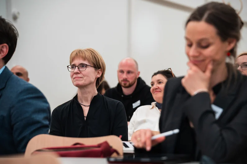 Fotoaufnahme von Astrid Ensslin während einer Konferenz am Tisch eines Hörsaals