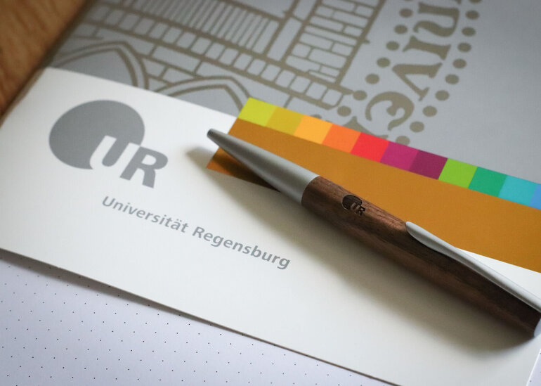 Mappe im Corporate Design der Uni Regensburg mit Kugelschreiber
