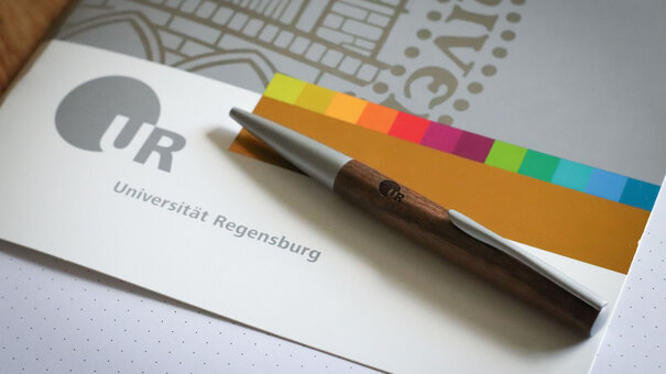 Mappe im Corporate Design der Uni Regensburg mit Kugelschreiber