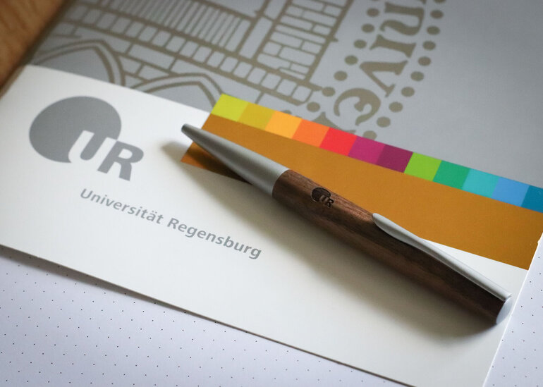 Mappe im Corporate Design der Uni Regensburg mit Kugelschreiber