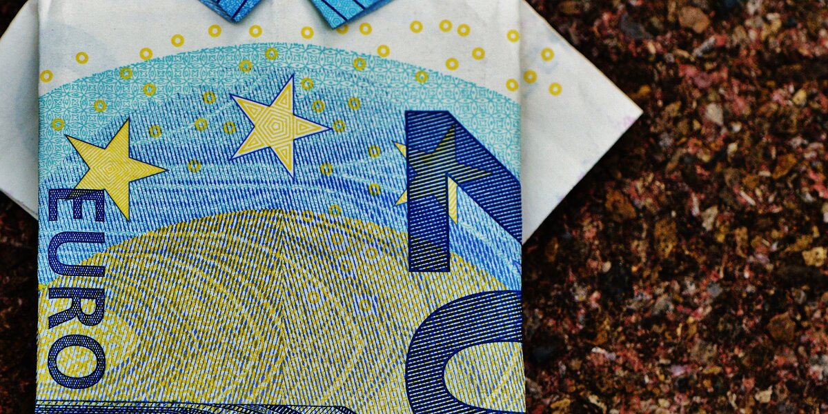 20€ Schein, zu einem Polohemd zusammengefaltet vor braunem Hintergrund.