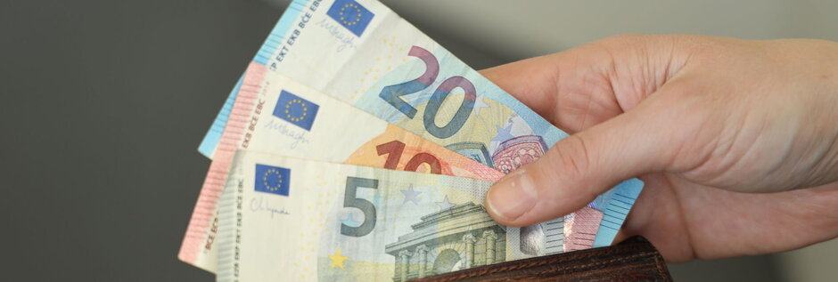 Person, die Geldscheine aus einem Geldbeutel nimmt