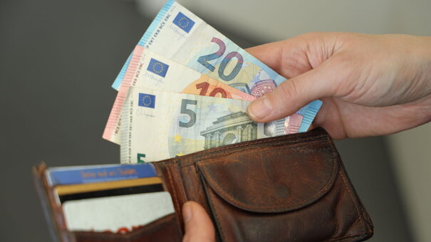 Person, die Geldscheine aus einem Geldbeutel nimmt